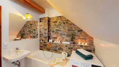 The bathroom with a bath by the stone wall