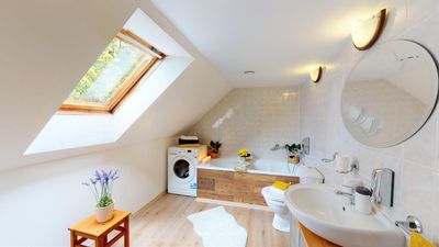 The bathroom with a bath, washing machine and roof window