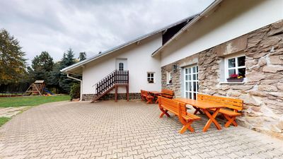 Paved courtyard with wooden tables and benches in front of the house