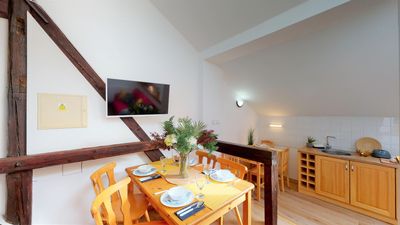 A laid dining table, with the kitchen and television behind