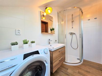 The bathroom with a shower and a washing machine