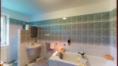 The bathroom with a bath and green tiles