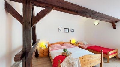 A bedroom with a double bed and single beds under the beams