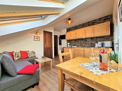 The living area with a dining table and the kitchen by the stone wall