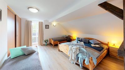 Ložnice apartmánu s manželskou postelí, dvěma jednolůžky a vstupem na balkon